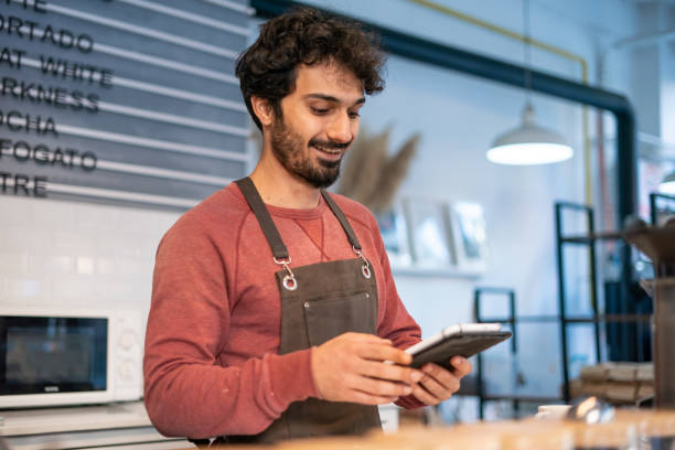 istock Young barista man using tablet in coffee shop 1352953000