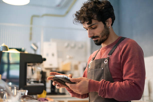 istock Young barista man using tablet in coffee shop 1352953003
