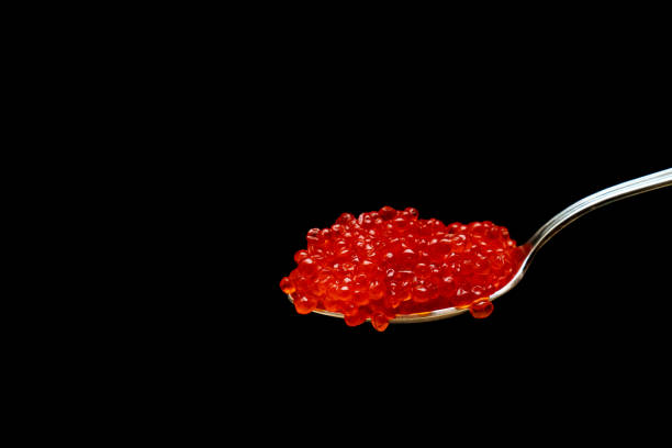 istock Red Caviar in silver spoon on black background with copy space. Close-up red salmon caviar. 1352953574