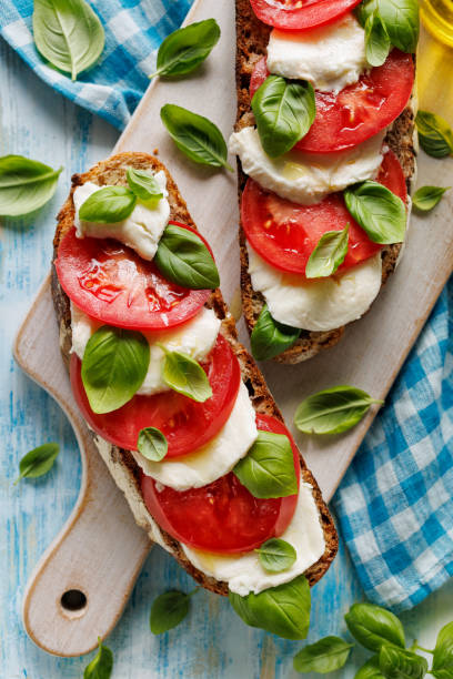 istock Caprese open faced sandwich based on sourdough bread with the addition of tomatoes, mozzarella cheese, fresh basil and olive oil 1352953994