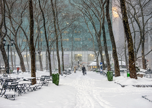 New York City, USA - February 13, 2014: Pedestrians trying to walk on snow-covered streets under heavy snowstorm in Bryant Park in New York, USA