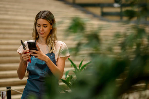 istock Florist taking care of a plant while using pruning shears and a smartphone 1352960147