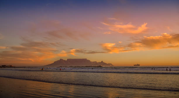 istock Dramatic sky at sunset beach in Bloubergstrand cape town with table mountain at back drop 1352960182