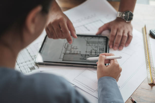 Architect or Engineer team designer discussing detail drawing on digital tablet. stock photo