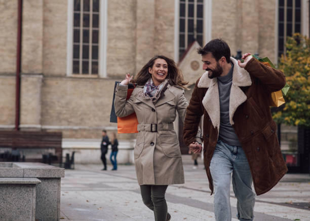 istock A young man is holding his girlfirend's hand while they roun down the street. 1352970571