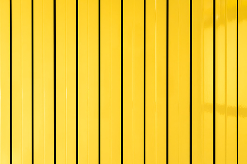 Iron fence. Yellow metal plate with a corrugated pattern of vertical lines.