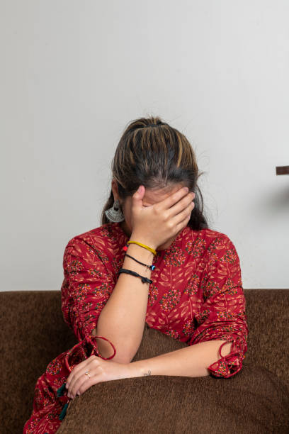 Young indian girl getting sad, covering her face because of sadness. A girl crying while sitting on the couch. Young indian girl getting sad, covering her face because of sadness. A girl crying while sitting on the couch. singh stock pictures, royalty-free photos & images