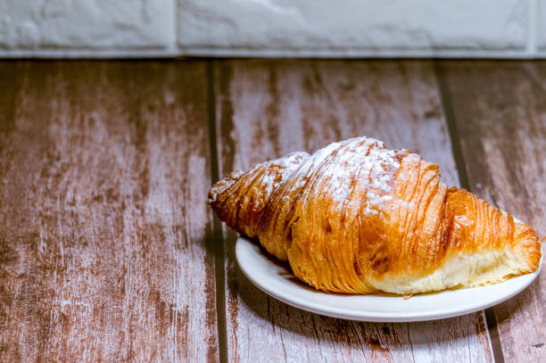 istock Croissants sprinkled with icing sugar in a white plate on a wooden table. 1352985281