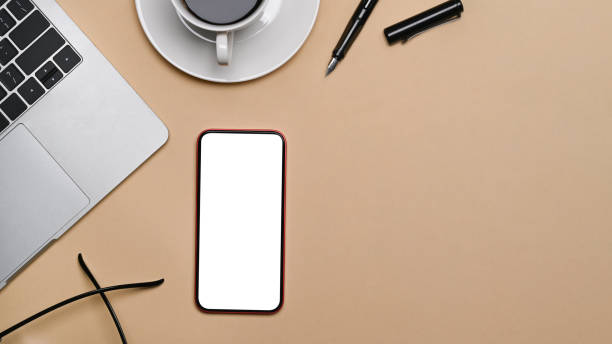istock Smart phone with blank screen and laptop computer on beige background. 1352990444