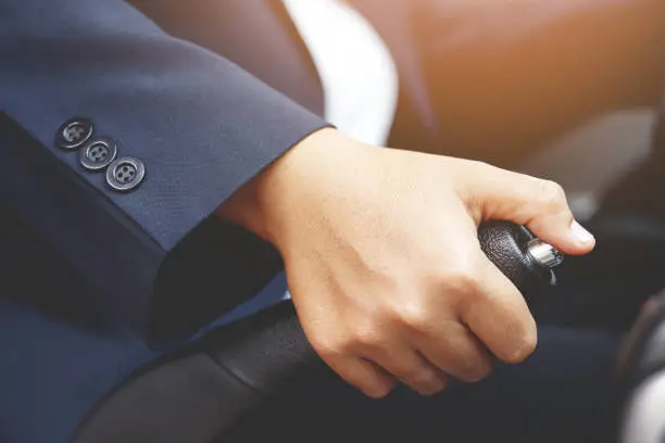 Closeup of person hand pulling handbrake lever in car For safety while parking.