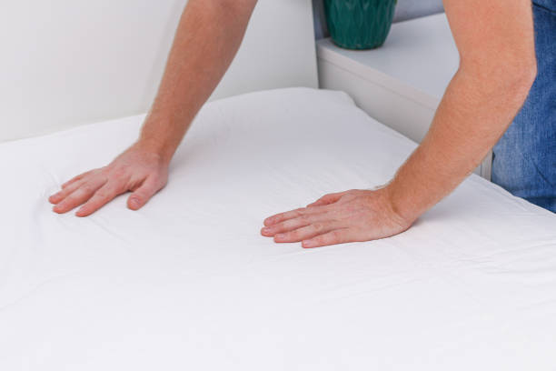 istock A man puts an elasticated sheet on mattress. Change of bed linen. 1352995390