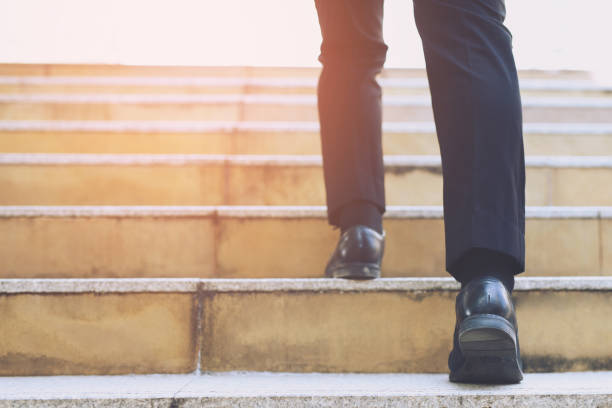 fermer les jambes chaussures de jeune homme d’affaires une personne marchant marcher en haut des escaliers dans la ville moderne, monter, le succès, grandir. avec filtre tons rétro vintage effet chaud. escalier - lace one person vitality action photos et images de collection