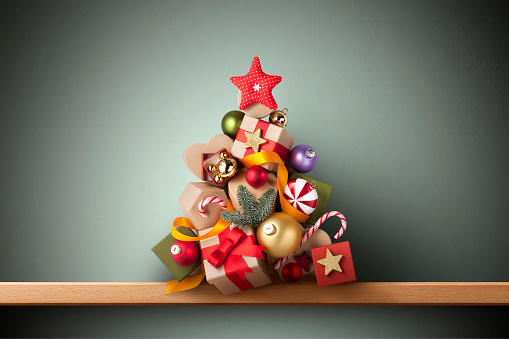 Christmas tree made ​​of gifts and decorations on shelf.