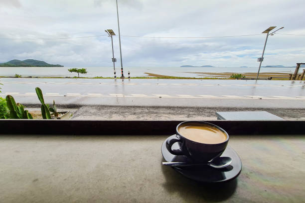 caneca de xícara de café em mesa de madeira com praia de mar de rua e paisagem de fundo do oceano - tranquil scene sky street road - fotografias e filmes do acervo