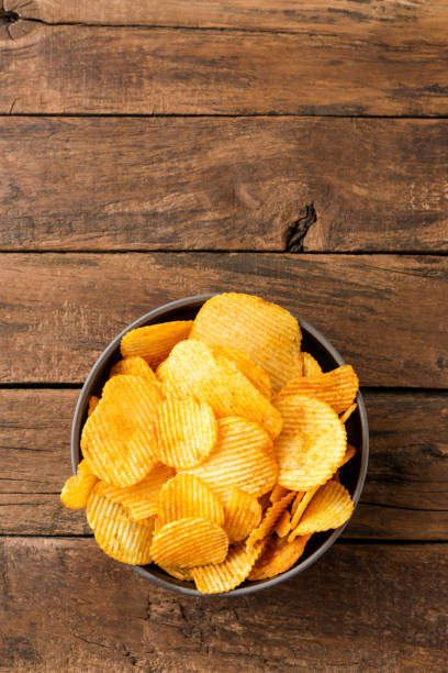 Potato chips in bowl on rustic wooden background with copyspace. Top view stock photo