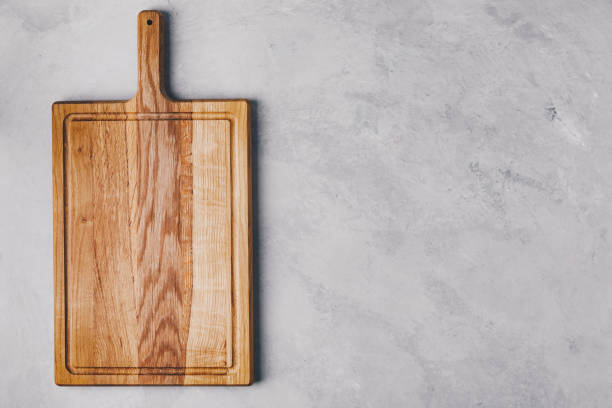 istock A wooden cutting board on gray concrete stone background. Top view, copy space. 1353011465