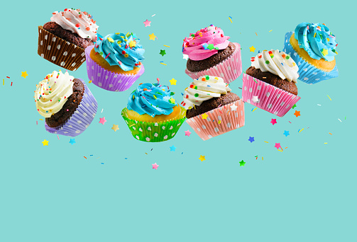 Delicious Cupcakes for party, birthday. Various cupcakes falling over aqua blue background