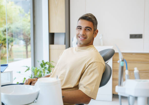 歯科医の椅子に座っている幸せな若者の肖像画 - dentist dentists chair men confidence ストックフォトと画像
