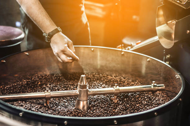 processo di tostatura del caffè artigianale professionale. tamburo di metallo pieno di chicchi di caffè - roasted machine bean mixing foto e immagini stock