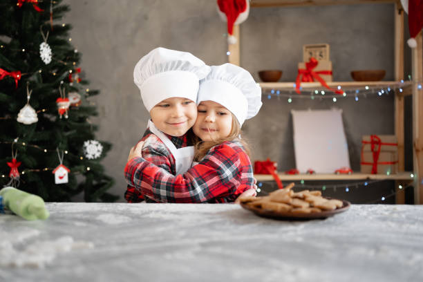 children baker brother and sister made homemade christmas cookies in the kitchen. a boy and a girl in a chef's cap and apron with gingerbread - pastry cutter family holiday child imagens e fotografias de stock