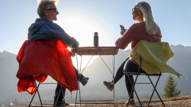 istock Couple enjoy hot beverage on a mountain ridge at sunset 1353024634
