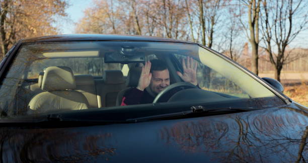 istock Emotional man in car, view through windshield. Aggressive driving behavior. Angry man driver hitting the steering wheel with his fists. 1353029252