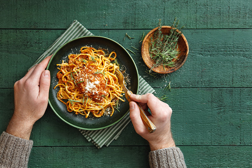 Classic spaghetti bolognese with parmesan cheese and herb. Flat lay top-down composition on dark green background.
