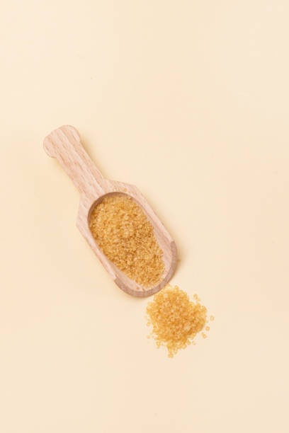 istock Brown Sugar in Wooden Scoop Vertical Yellow Background 1353038765