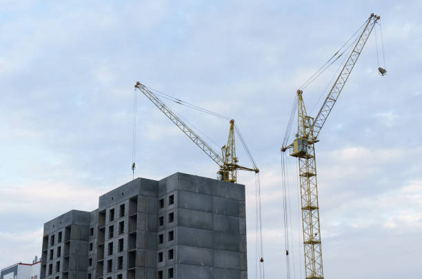 istock Against the background of the sky, there is a multi-storey building under construction and two cranes 1353040422