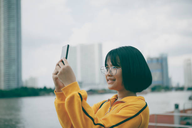 istock asian teenager raising mobile phone and looking into device screen 1353040480
