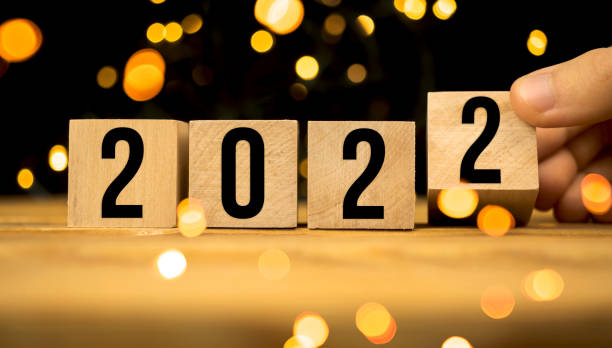 istock Hand changes wooden cubes to 2022 Happy New Year concept background with bokeh 1353042166