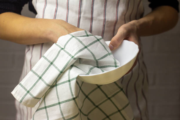 istock A young man wipes a plate with a cotton towel. 1353045087