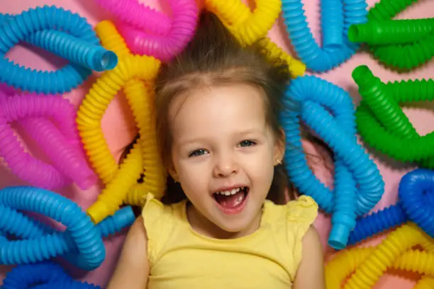 Photo of Child surrounded by a large number of popular modern pop tubes toy.