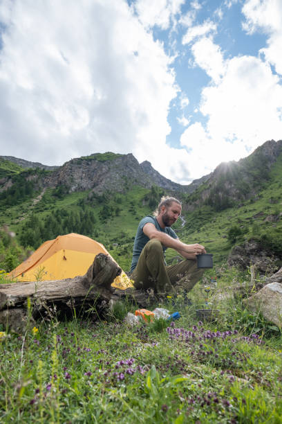 istock Male hiker preparing lunch by the campsite 1353059281