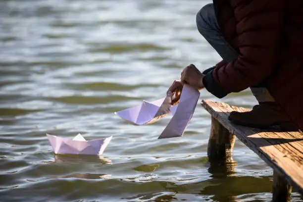 Side View of a Woman Putting Paper Boats in the Sea.