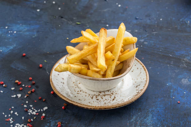 French fries in white bowl isolated on blue background stock photo