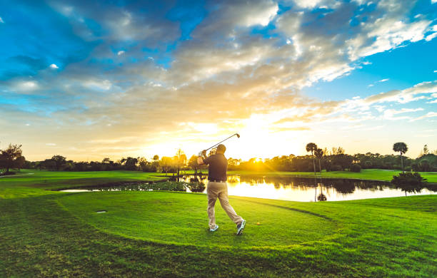 istock Man on a idyllic scenic golf course swinging golf club at sunset 1353062717