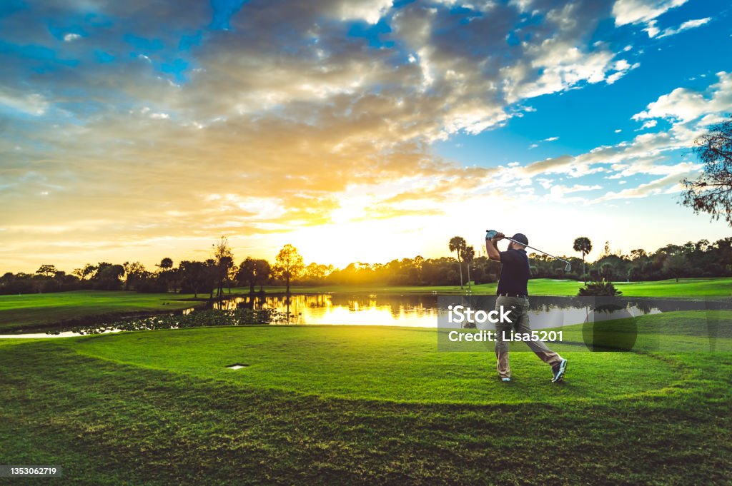 Man on a beautiful scenic sunset golf course swings a golf club Man golfing on a golf course in south Florida. Okeeheelee golf course in West Palm Beach Florida Golf Stock Photo