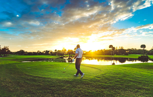 istock Man on a scenic idyllic sunset tropical golf course  with golf club 1353062809