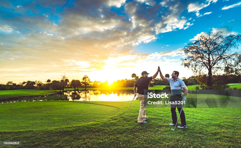 Two male golfers high five on a scenic sunset golf course Two men golfing together on Okeeheelee golf course in West Palm Beach Florida Golf Stock Photo
