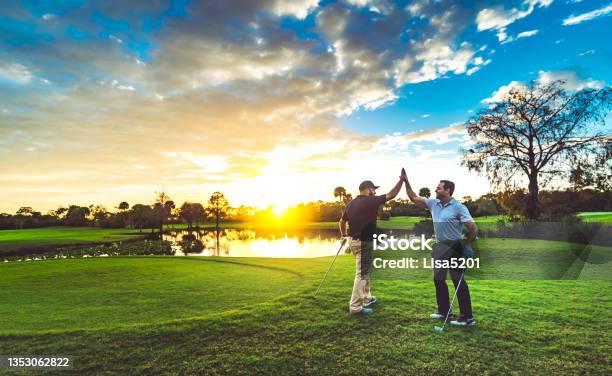 Two Male Golfers High Five On A Scenic Sunset Golf Course Stock Photo - Download Image Now