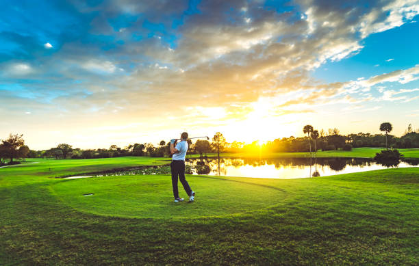l’homme sur un magnifique parcours de golf pittoresque au coucher du soleil balance un club de golf - golf golf swing sunset golf course photos et images de collection