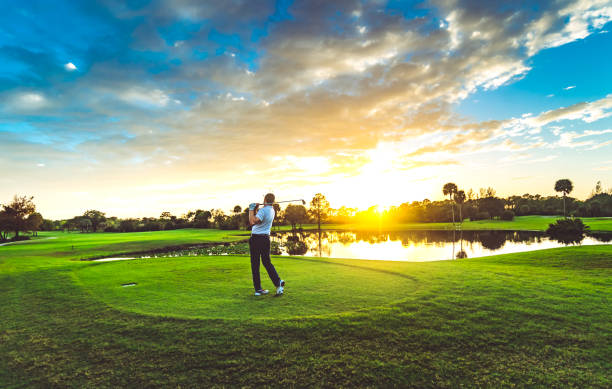 homem em um lindo campo de golfe pôr do sol cênico balança um clube de golfe - golf swing golf teeing off men - fotografias e filmes do acervo