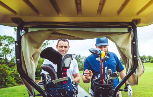 ゴルフカートの後ろから自分のクラブを選択してゴルフをしている2人の男友達 - golf cart golf bag horizontal outdoors ストックフォトと画像