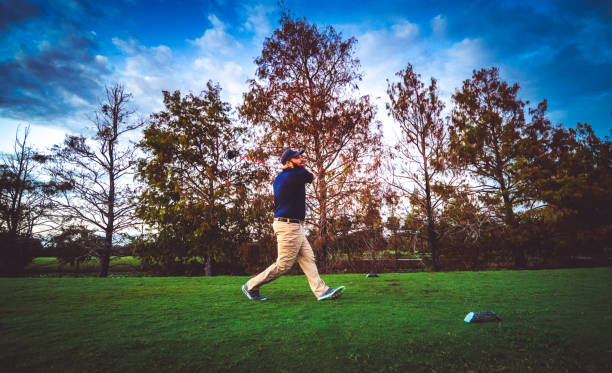 istock Man on a scenic golf course swings a golf club teeing off 1353064213