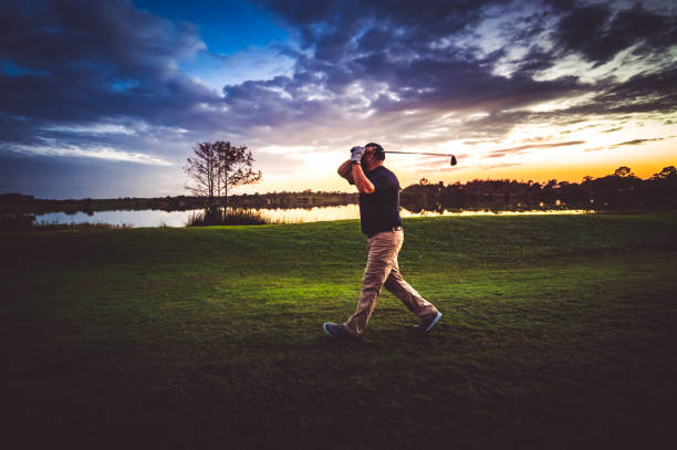 istock Man on a scenic sunset tropical golf course taking a swing 1353064215