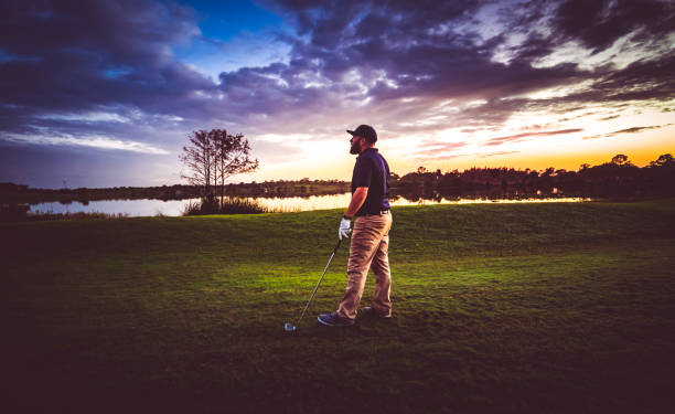 istock Man on a scenic sunset tropical golf course with golf club 1353064840
