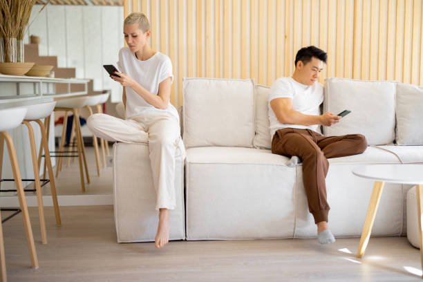 istock Couple using smartphones on sofa at home 1353065164