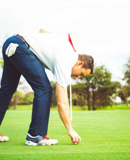 istock Man picks up his golf ball and set his tee on a golf course 1353065382