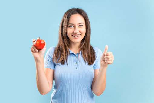 Smiling happy young woman holding an apple. Healthy nutrition, diet food concept